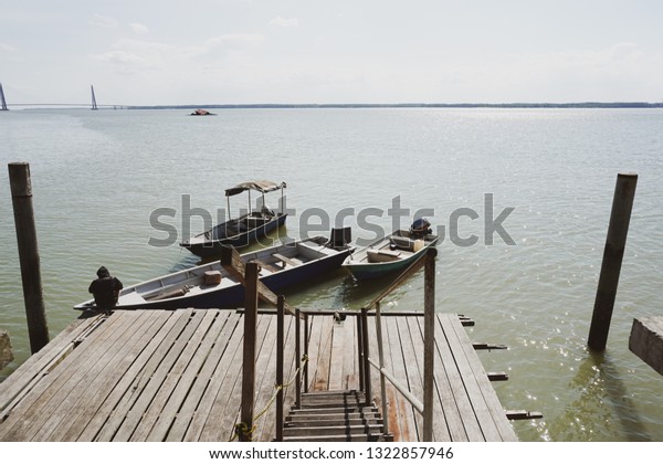 A man tie a rope to secure his boat to a\
wooden jetty. view from a wooden\
jetty