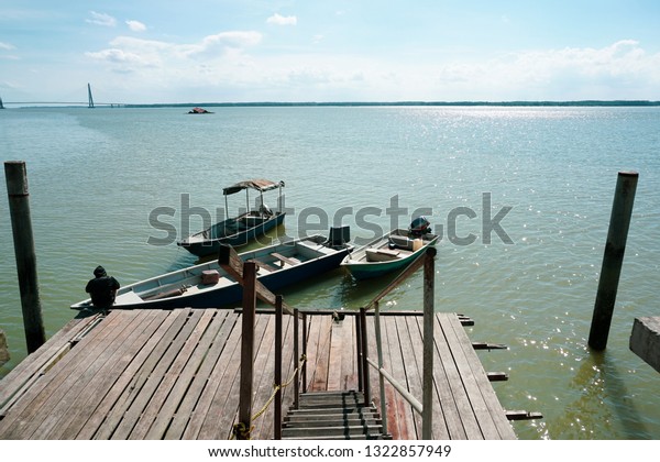 A man tie a rope to secure his boat to a\
wooden jetty. view from a wooden\
jetty