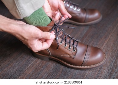 Man Tied Shoelaces On His Leather Boots On Wooden Floor Closeup