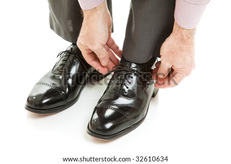 Man ties his shiney new black leather business shoes.  Isolated on white.