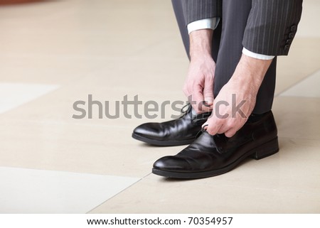 Man ties his shiney new black leather business shoes.