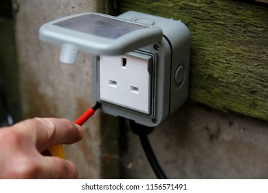 Man Tightening External Socket Box With An Electrical Screwdriver Outdoor Outside