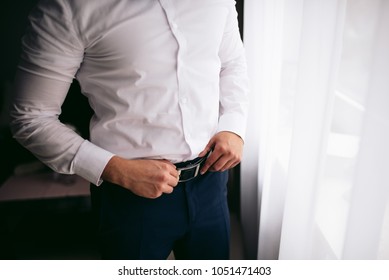 Man tightens the black leather belt on the black pants  - Powered by Shutterstock