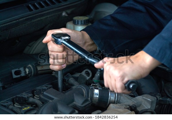 Man tightens spark\
plug with torque wrench
