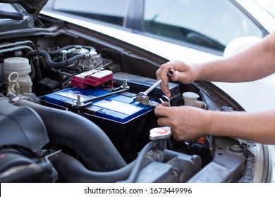 a man tightens with a wrench bolts for fastening a new battery, installing spare parts for a car - Shutterstock ID 1673449996