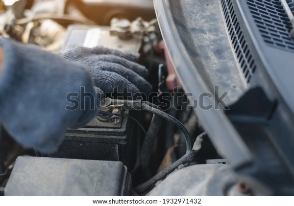 a man tightens with a
wrench bolts for fastening a new battery, installing spare parts
for a car