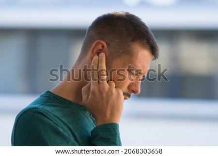 Man with tinnitus. Man touching his ear because of strong earache or ear pain. Otitis
