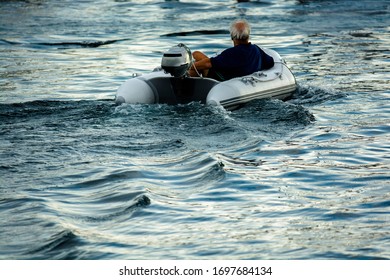 Man In Tiny Motor Boat Leaves The Harbor