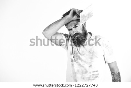 Man with tired face touches forehead. Hard labour concept. Man with beard in dirty shirt, copy space. Builder, plasterer, repairman, foreman holds putty knife, plastering tool, white background.