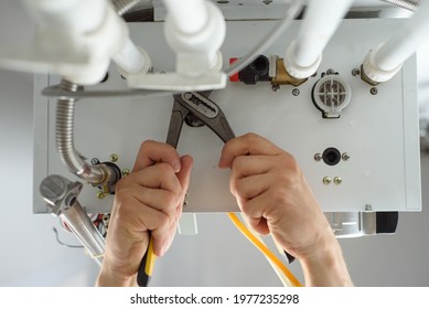 A Man With Tools Checks The Pipes That Fit The Gas Heating Boiler.