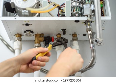 A Man With Tools Checks The Pipes That Fit The Gas Heating Boiler.