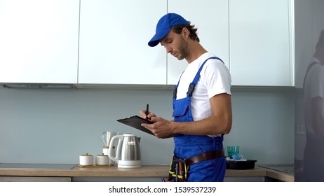 Man With Tools Writing Report Inspecting Kitchen On Electrical Safety, Service