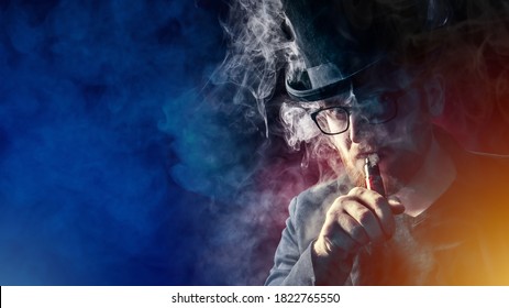 A man in a top hat smokes an electronic cigarette and looks at the camera. VAPE shop. Vaper on a dark background. Place for the text. A serious man with an e-cigarette.