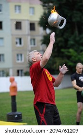 Man Tosses Burning Kettlebell Standing On A Lawn, Juggling. Day Of Kyiv City Celebration. June 20, 2019.Kiev, Ukraine