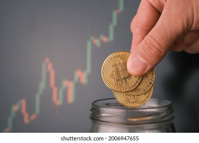 Man tosses a few bitcoin into a glass jar or piggy bank to accumulate a budget. - Shutterstock ID 2006947655