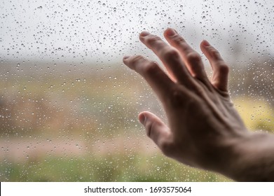 Der Mensch berührt regengetränkte Fensterscheibe als Symbol für Wanderlust und Sehnsucht