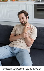 Man Touching Arm While Feeling Pain At Home