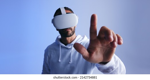 Man touching a button in virtual space. Young man interacting with the metaverse using a virtual reality headset. Young man experiencing a 3D simulation. - Shutterstock ID 2142734881