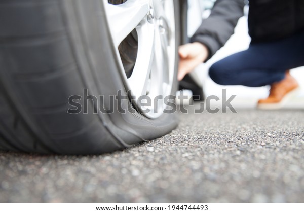 man touching a flat\
tire on the roadside