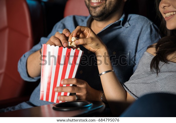映画館でポップコーンを手にしながらデートの手を触る男 の写真素材 今すぐ編集