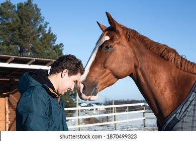 Man Is Touching Horse's Nose With His Forehead