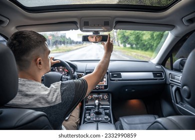 A man touching and looking at rearview mirror.