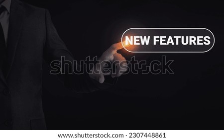 Man touching new features concept typography with glowing light and dark backdrop. Technology new features concept background