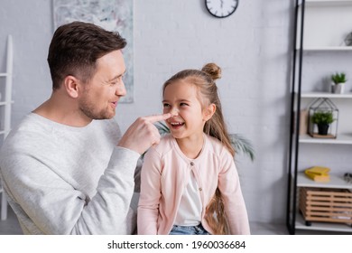 Man Touching Nose Of Positive Kid In Living Room