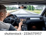 Man touching screen of a GPS navigation system in his car.