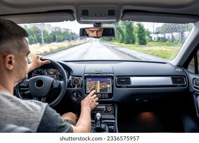 Man touching screen of a GPS navigation system in his car.