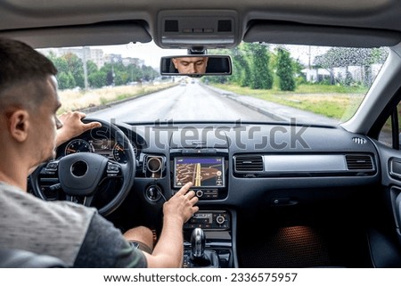 Man touching screen of a GPS navigation system in his car.