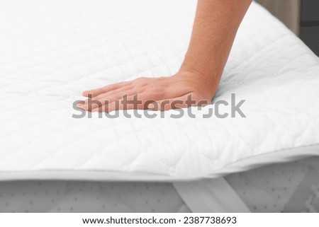 Man touching soft mattress with protector, closeup