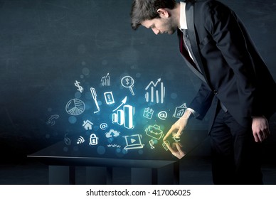 Man touching technology smart table with business icons and symbols