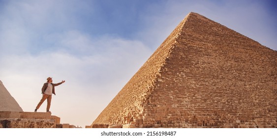 Man tourist with hat stand background of pyramids Cairo Egypt, sunlight. Concept travel banner.