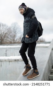 Man in town in winter. Dark blue color in clothes. Modern young man of tall stature.