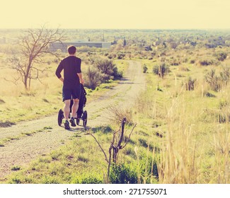 Man Trail Running With A Pram In The Foothills With A City View With A Retro Instagram Filter