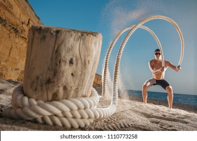 Man Training With Battle Rope On The Beach. Athlete Doing Cross Fitness Workout Outdoor. Sport Fit Exercise.