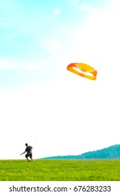 Man is training to catch wind in the field with a kite	

