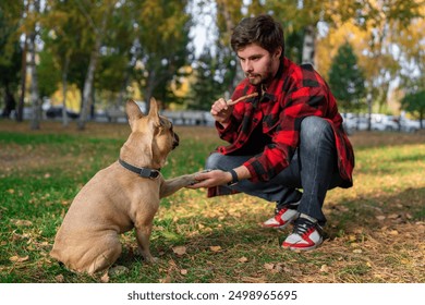 A man is training his dog using treats in the park, building a bond on a pleasant autumn afternoon - Powered by Shutterstock