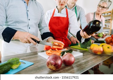 Man in training kitchen cutting vegetables under watchful eye of competent dietician - Powered by Shutterstock