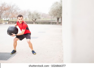 Man Training With The Medicine Ball Against The Wall