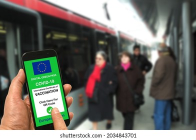 A man at a tram stop holds a smartphone with the European Union digital green pass for Covid-19 in his hand. Safe travel concept during the Coronavirus and the Green pass