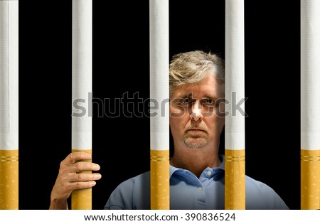 A man is trapped behind a prison of cigarettes representing nicotine addiction, depression and the struggle to quit smoking.