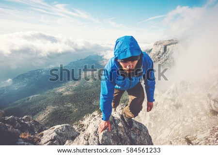 Man Traveler climbing on mountain summit over clouds Travel Lifestyle success concept adventure active vacations outdoor extreme sport