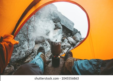 Man traveler cooking in pot on stove burner relaxing in camping tent Travel Lifestyle concept vacations outdoor mountains vacations