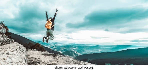 Man traveler on mountain summit enjoying nature view with hands raised over clouds - Sport, travel business and success, leadership and achievement concept - Shutterstock ID 2064005291