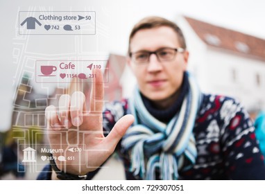 Man Traveler Points A Finger On The Map. View Through The Phone Screen. Augmented Reality In Marketing Concept