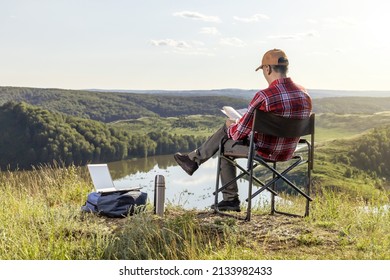 Man Traveler Reading Book Outdoor In Mountains At Sunset. Remote Work Concept. Hiking Active People Lifestyle.