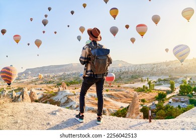 Man traveler vacations in beautiful destination in Goreme, Turkey. Fabulous Kapadokya with flying air balloons at sunrise, Anatolia