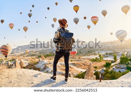 Man traveler vacations in beautiful destination in Goreme, Turkey. Fabulous Kapadokya with flying air balloons at sunrise, Anatolia